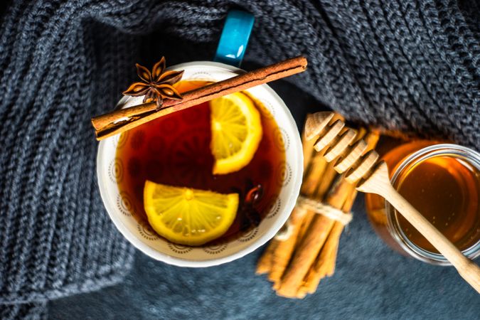 Top view of cup of tea with lemon slice surrounded by knitted scarf