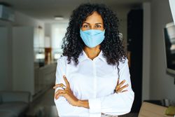 Portrait of confident woman in facemask with her arms crossed