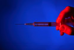 Anonymous person with syringe in neon lighting