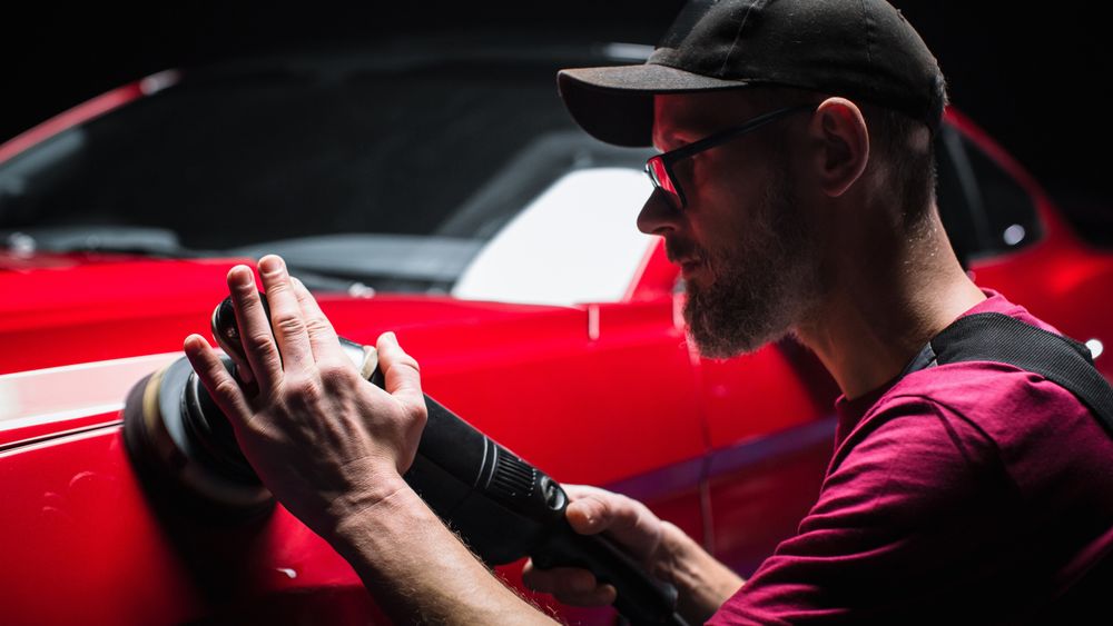 Portrait of an Adult Man Working in a Detailing Studio, Prepping a Factory Fresh American Sportscar for Car Care Treatment.