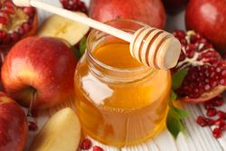 Close up of honey pot surrounded by autumn fruit