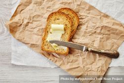Buttered toast with knife on craft paper 4AWqm0