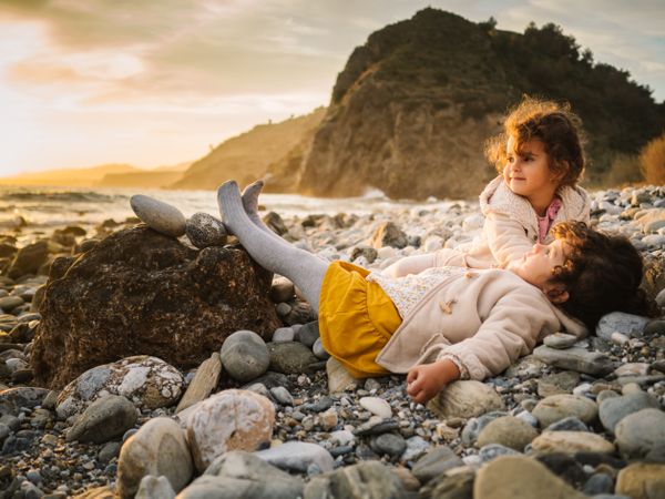 Cute girls resting on stony beach in evening