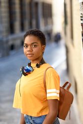 Female in yellow t-shirt and headphones standing on street
