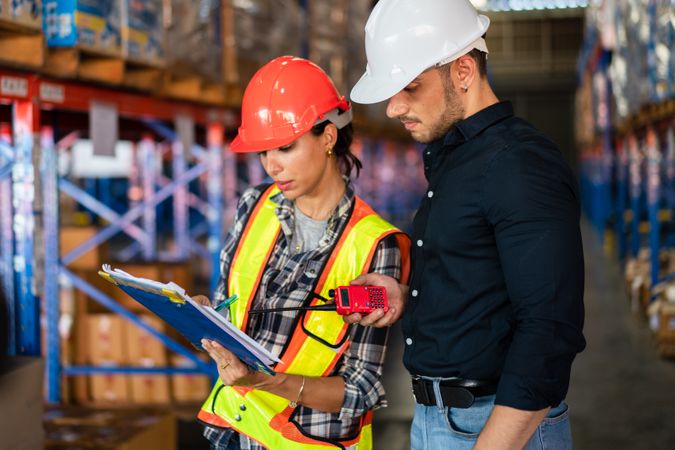 Warehouse supervisor and female operator reviewing documents