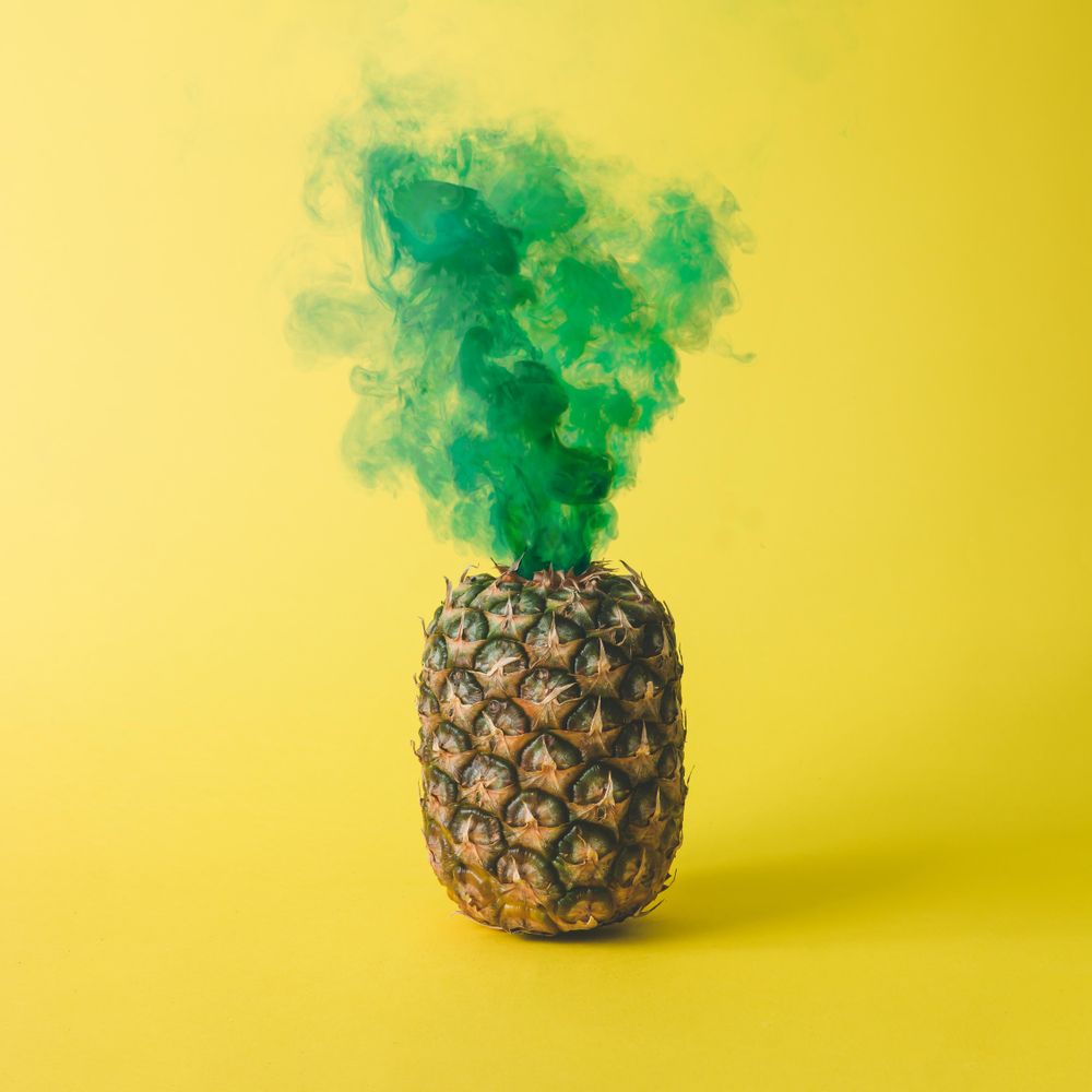 Pineapple with green smoke on bright yellow background