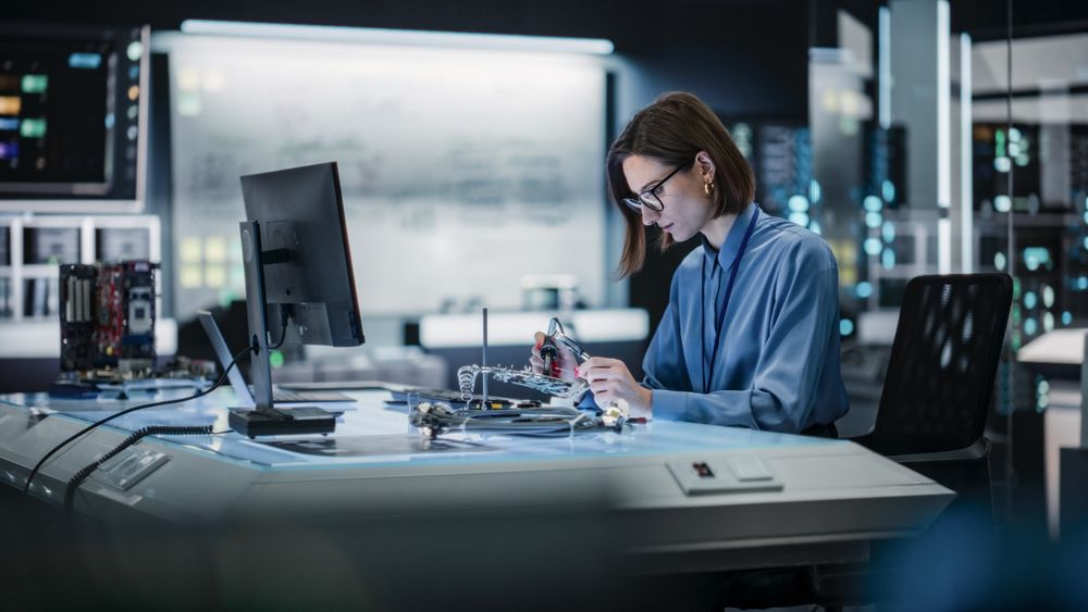 Portrait of Female Specialist Soldering a Circuit Board in a Technologically Advanced Company. Focused Female Engineer Working on a Project, Testing Theory in a Manufacturing Research Facility