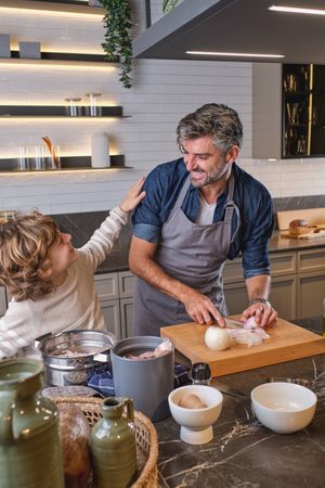 Positive father with son cooking in kitchen