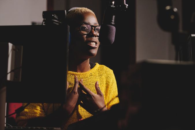 Black woman speaking into microphone in recording studio