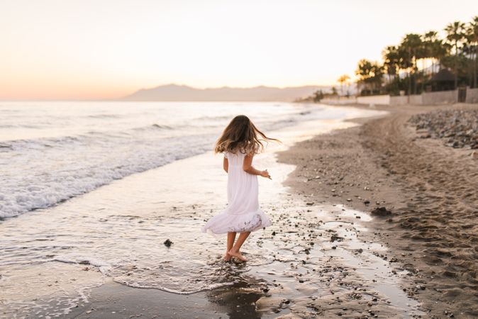 Excited girl running along beach in daylight
