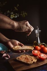 Crop person pouring salt on toasts