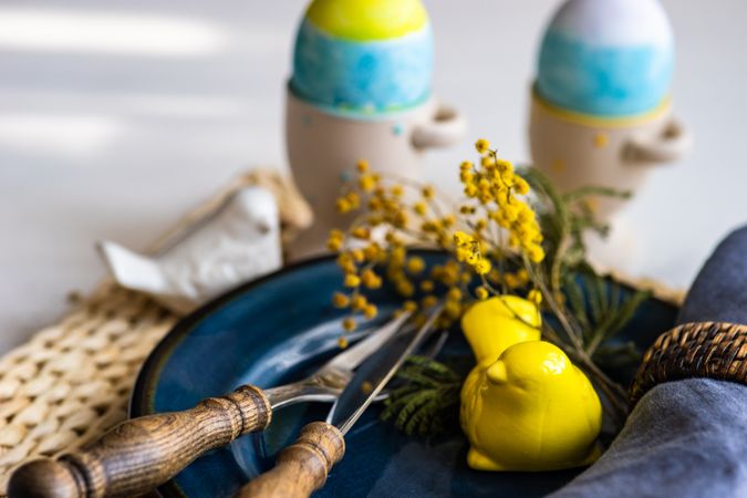 Easter holiday concept with navy plate with bird ornament and decorative eggs in cups