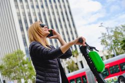 Woman talking on smartphone and riding electric scooter