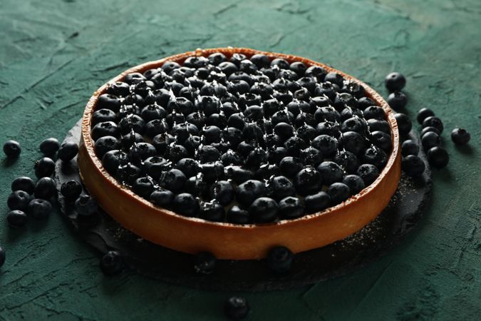 Tray with blueberry pie on green background