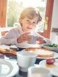 Smiling kid having breakfast in dining room