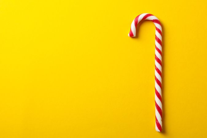 Sweet candy cane on yellow background, space for text