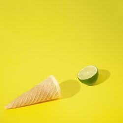Ice cream cone with lime half on yellow background