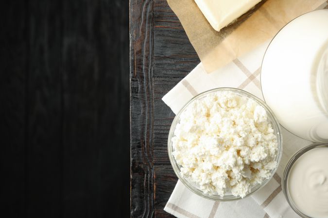 Fresh dairy products and towel on wooden background, top view