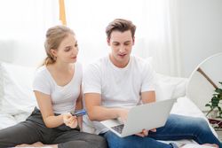 Young couple relaxing at home with laptop and credit card