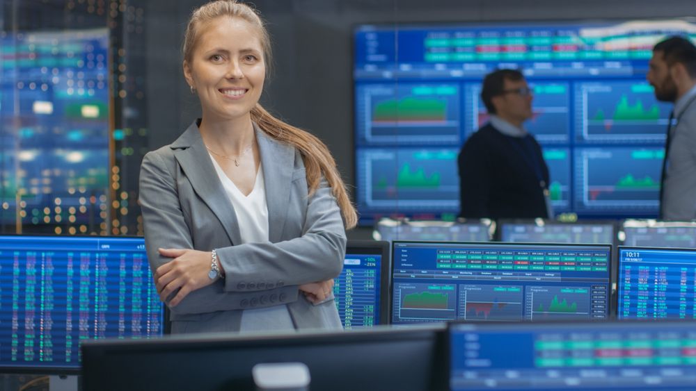 Successful Female Stock Trader Crosses Arms and Smiles at the Camera.