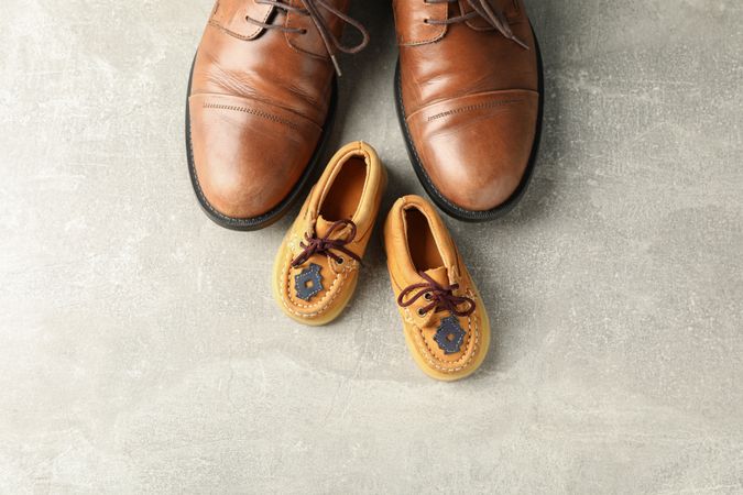 Brown leather shoes and children's shoes on grey background, space for text and top view