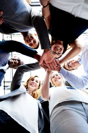 Shot looking up at colleagues smiling in a huddle, vertical