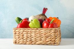 Wicker basket and vegetables on wooden background, copy space