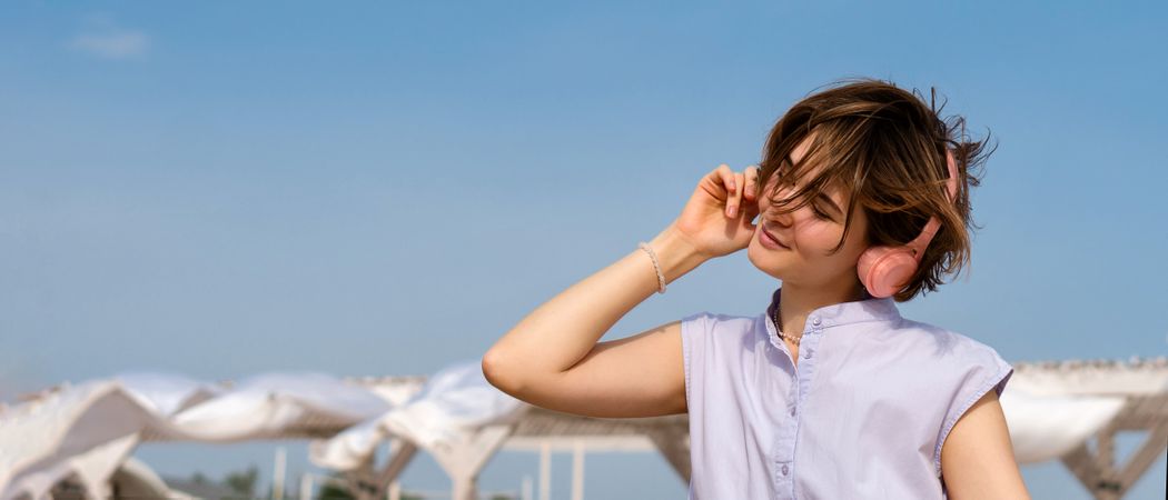 Woman listens to music with headphones outdoors