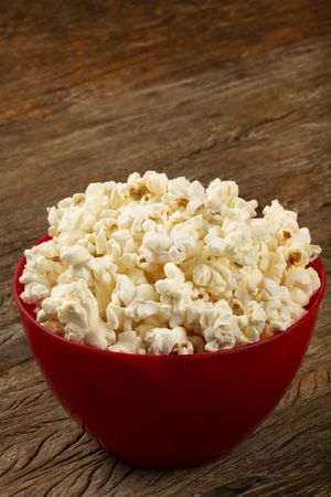 Bowl with salted popcorn sore the table.