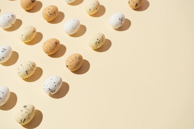 Speckled eggs  in rows on pastel yellow background