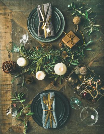 Festival holiday table setting on wooden table, with gold ornaments and branches
