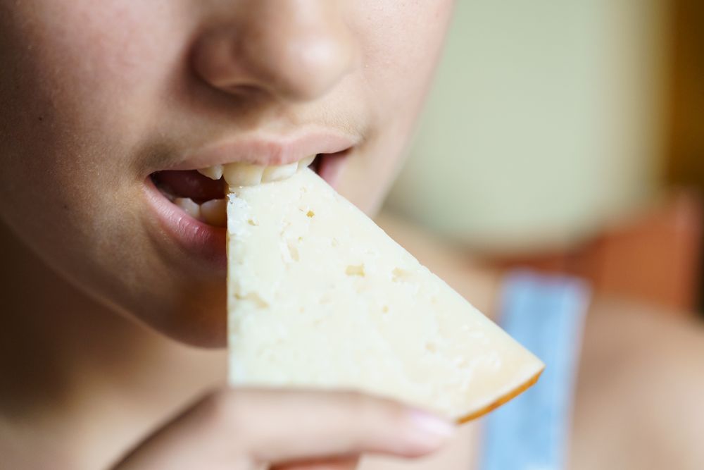 Teenager biting into slice of cheese