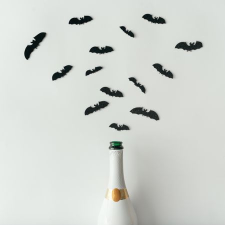 Champagne bottle with bats silhouettes on light background