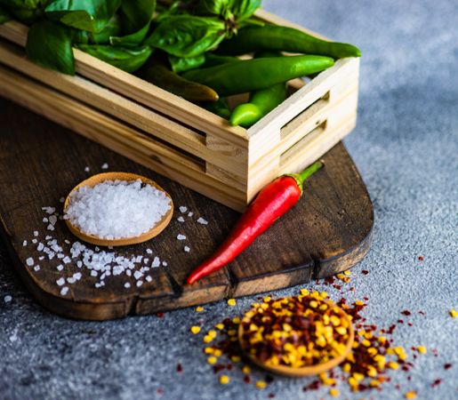 Peppers and herbs in basket on cutting board