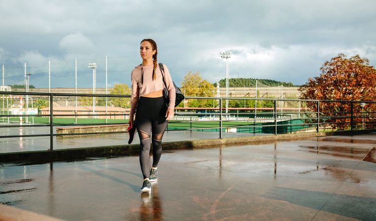 Sportswoman with gym bag and sports shoes walking to go to training