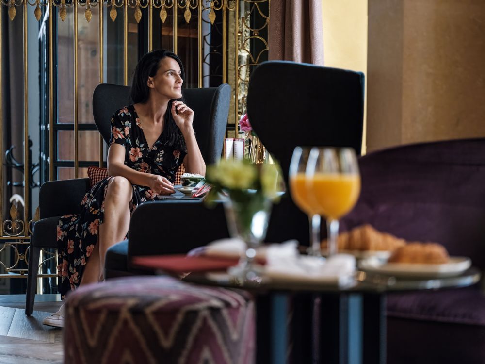 Stylish woman sitting at table in cafe of hotel