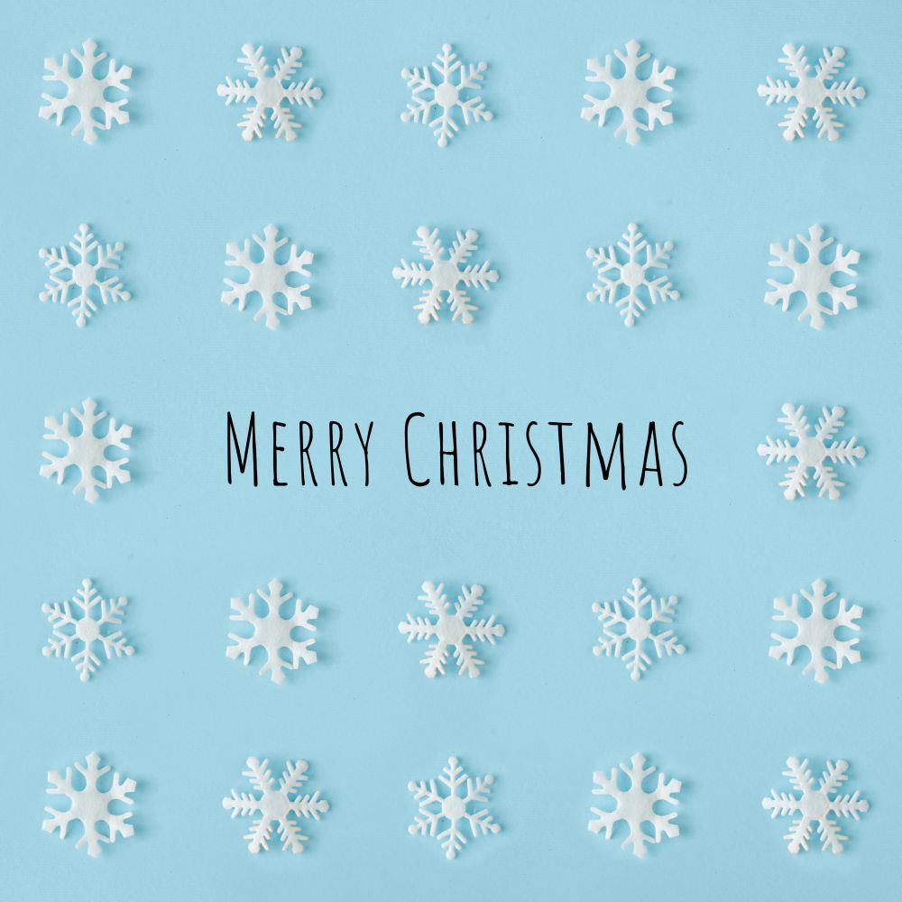 Snowflakes arranged on blue background with “Merry Christmas”