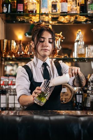 Female bartender preparing a cocktail in a traditional cocktail bar