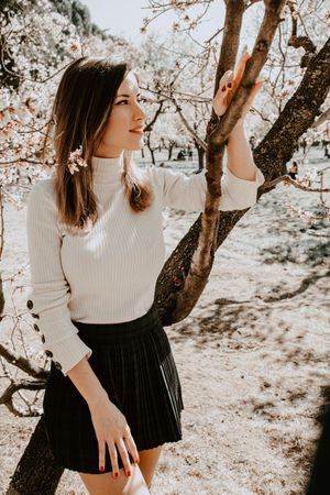 Young happy woman between trees in garden