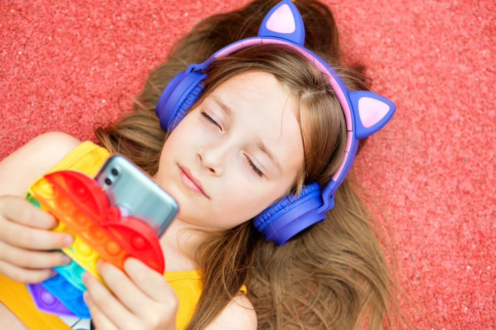 School girl with colorful toy and smartphone