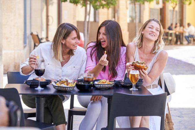 Content female friends eating dinner in restaurant on street