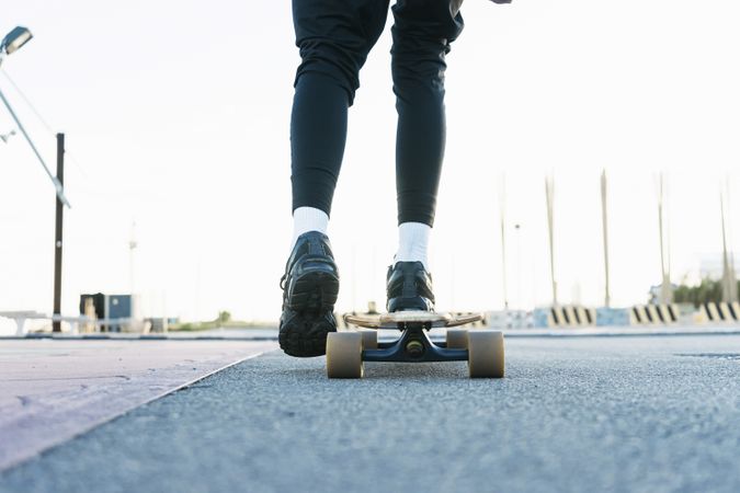 Feet of unrecognizable woman riding on longboard