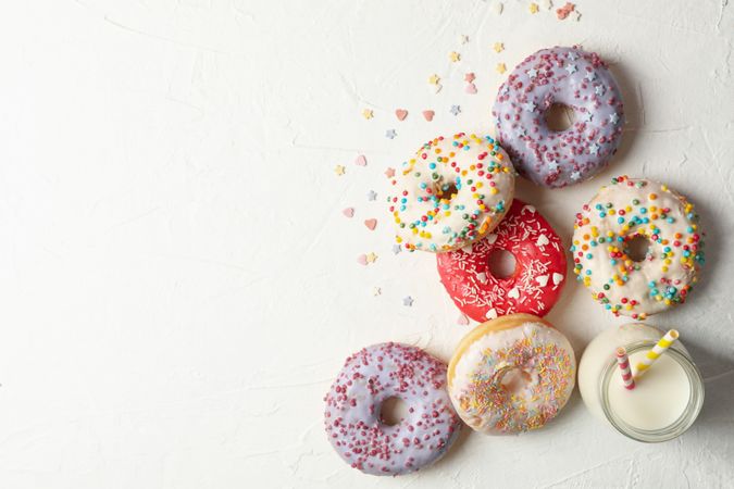Milk and tasty donuts on plain background, top view