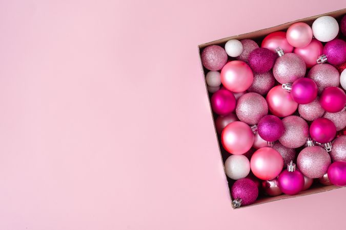 Box of pink festival baubles on pink background