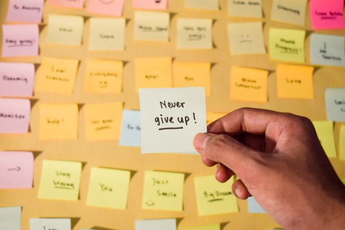 Hand hold sticky notes with words Never Give Up