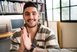 Male creative smiling with hands together in thank you sign in relaxed modern office 0JZVd0
