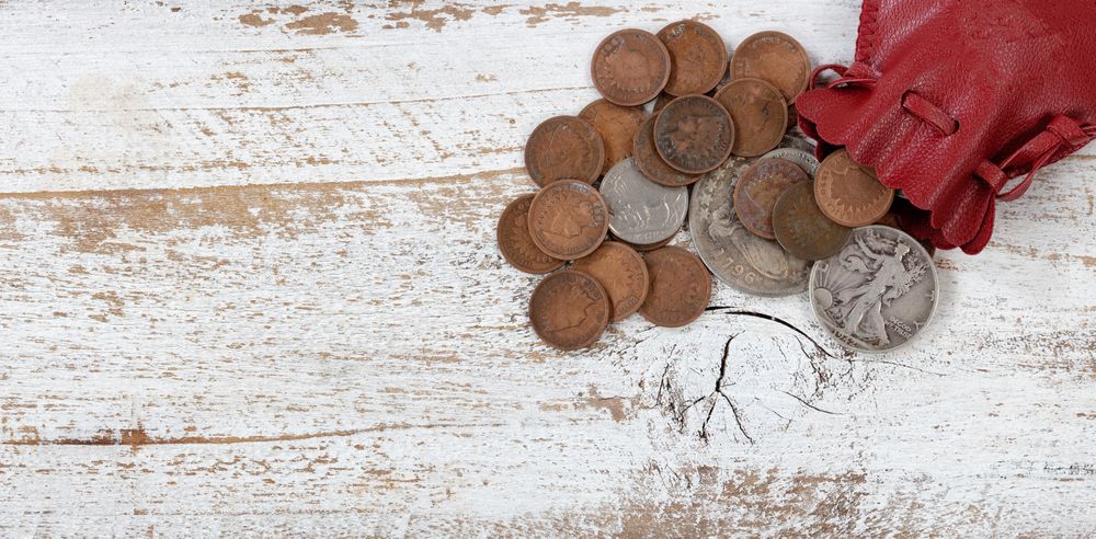 Leather bag of rare United States coins on rustic wood
