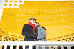 Mature man and woman holding each other under a bright gazebo 47WWk4