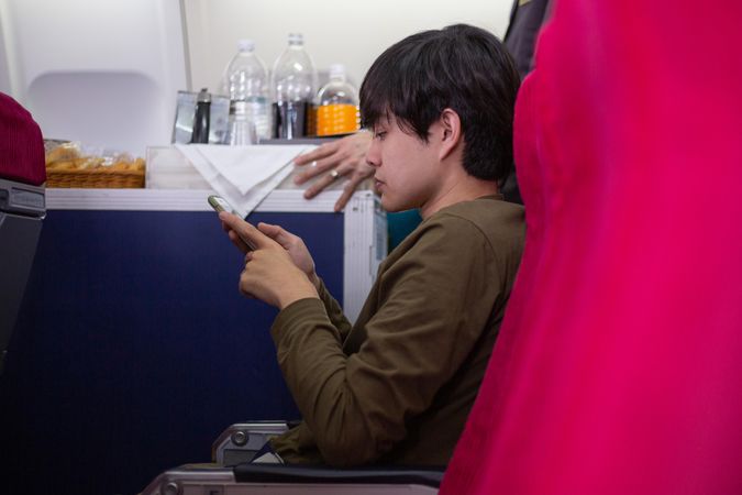 Asian passenger using mobile phone seated in an airplane