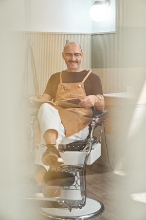 Stylish barber reading book in barbershop